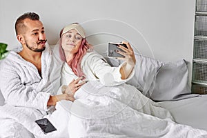 Couple on bed take photo on smartphone