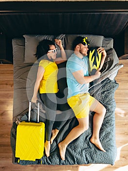 couple in bed with travel bag ready for summer sea vacation