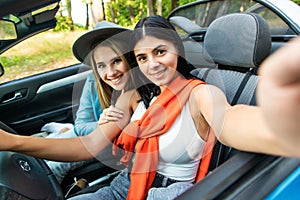 Couple of best friends women taking a selfie at car trip. Two young girl having fun togheter smiling at the camera