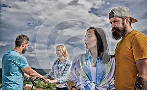 Couple with bicycle having great time while another couple bored. Couples spend leisure different way sky background