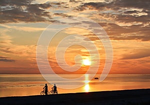 Couple of bicyclists walking along the seashore