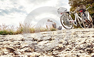 Couple on a bike trip. Lovers sitting on beach.