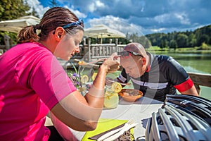 Couple biker dining outdoors on a lake after a bike tour around Lake Bloke in Nova Vas, Slovenia