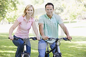Couple on bikes outdoors smiling
