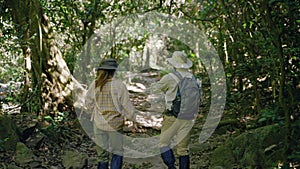 couple biologist on a forest walk collecting data is using binoculars to look into the treetops