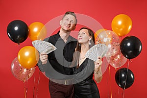 Couple in black clothes celebrating birthday holiday party hold lot cash money isolated on bright red background air