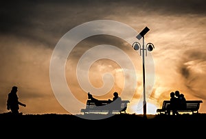 Couple black silhouette in love on benches at sunset