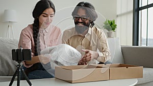 Couple bloggers customers open package box order online shopping delivery excited happy Arabian man and woman record