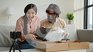 Couple bloggers customers open package box order online shopping delivery excited happy Arabian man and woman record