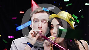 Couple, blow party horn and confetti in studio for celebration, success and winning of competition. Face of man and
