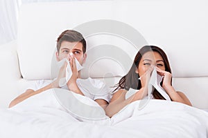 Couple Blowing Their Noses At Home