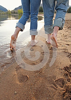 Couple in blue jeans walking on beach low angle