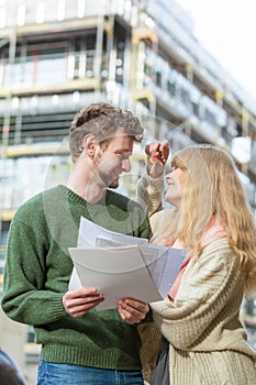 Couple with blueprint project keys on construction site