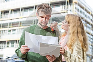 Couple with blueprint project keys on construction site