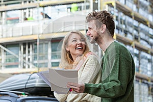 Couple with blueprint project keys on construction site