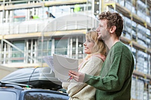 Couple with blueprint project keys on construction site