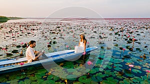 Couple in a boat at the Red Lotus Sea Kumphawapi full of pink flowers in Udon Thani Thailand.