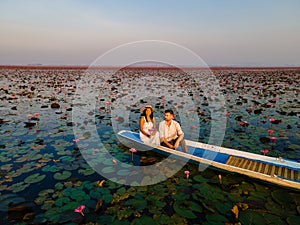 Couple in a boat at the Red Lotus Sea Kumphawapi full of pink flowers in Udon Thani Thailand.