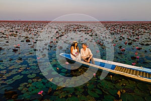 Couple in a boat at the Red Lotus Sea Kumphawapi full of pink flowers in Udon Thani Thailand.