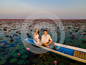 Couple in a boat at the Red Lotus Sea Kumphawapi full of pink flowers in Udon Thani Thailand.