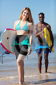 couple body boarders walking towards sea