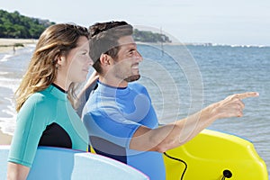 couple with boogieboards looking out over sea