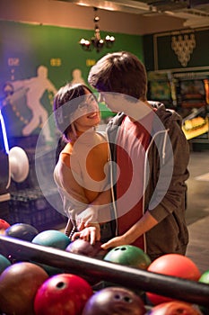 Couple in a bowling alley and holding a ball together