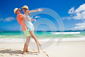 Couple in bright clothes on a tropical beach at Mahe, Seychelles.
