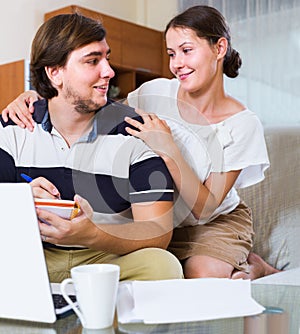 Couple browsing web and making notes indoors