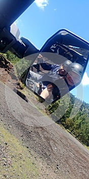 Couple on a buggy car capable on difficult terrain, can see the rear-view mirror and the road that leads to adventure