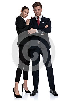 Couple in business suits with arms crossed and hands on shoulder
