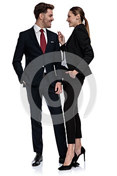 Couple in business suits standing together with hands in pockets