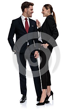 Couple in business suits standing together with hands in pockets photo
