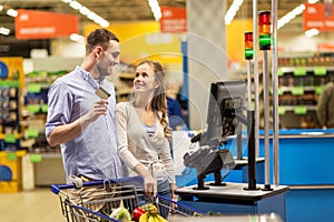 Couple buying food at grocery at cash register