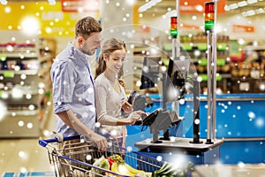 Couple buying food at grocery self-checkout