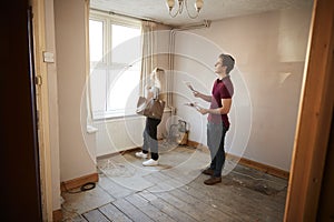 Couple Buying House For First Time Looking At House Survey In Room To Be Renovated photo