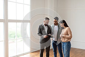 Couple Buying New Apartment, House Agent Showing Documents Blueprints