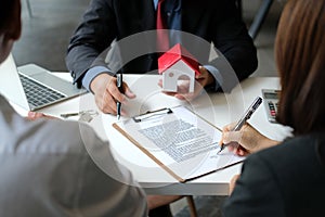 Couple buying renting house signing mortgage contract agreement with realtor real estate agent photo