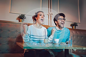 Couple in cafe looking happy after their favorite football team scored a touchdown