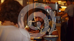 Couple in a cafe, man listen to music and dance a little, woman talk on phone