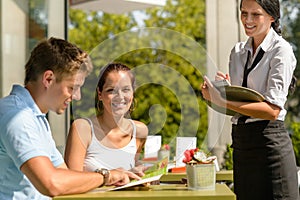 Couple at cafe ordering from menu waitress