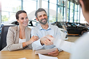 Couple with car dealer in auto salon