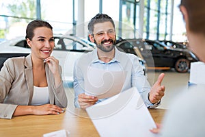 Couple with car dealer in auto salon