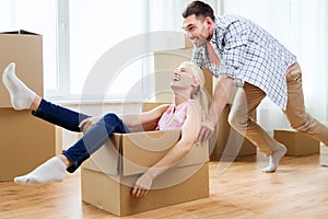 Couple with cardboard boxes having fun at new home
