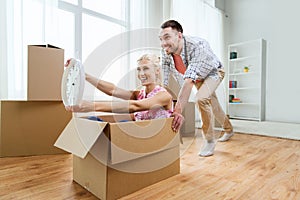 Couple with cardboard boxes having fun at new home