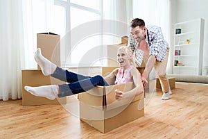 Couple with cardboard boxes having fun at new home