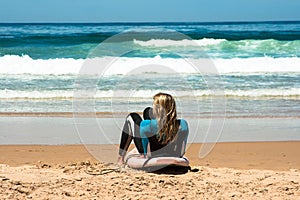 A woman in a wetsuit lies on the beach of Cordoama