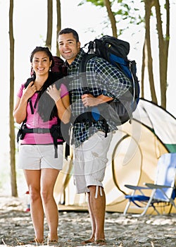 Couple carrying backpacks at campsite