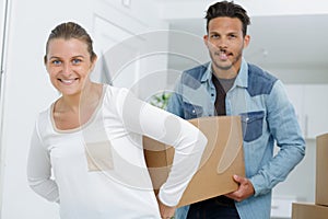 couple carrying box together in appartment