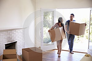 Couple Carrying Boxes Into New Home On Moving Day photo